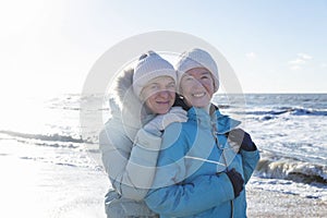 A happy family walks along the sandy seashore in winter. Laughing young and old women hugging. Love and tenderness