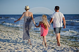 Happy family walks along the seaside holding hands.