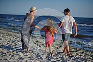 Happy family walks along the seaside holding hands.