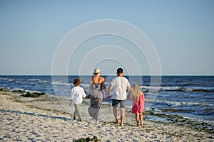 Happy family walks along the seaside holding hands.