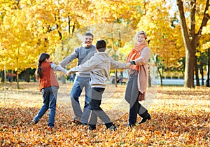 Happy family walks in autumn city park. Children and parents posing, smiling, playing and having fun. Bright yellow trees.