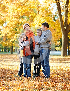 Happy family walks in autumn city park. Children and parents posing, smiling, playing and having fun. Bright yellow trees.