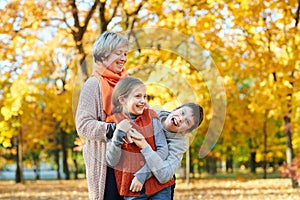 Happy family walks in autumn city park. Children and parents posing, smiling, playing and having fun. Bright yellow trees.