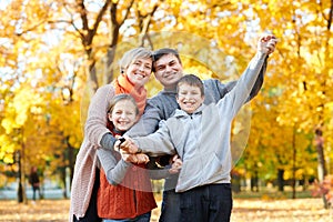 Happy family walks in autumn city park. Children and parents posing, smiling, playing and having fun. Bright yellow trees.