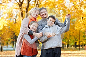 Happy family walks in autumn city park. Children and parents posing, smiling, playing and having fun. Bright yellow trees.