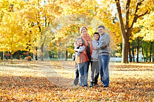 Happy family walks in autumn city park. Children and parents posing, smiling, playing and having fun. Bright yellow trees.