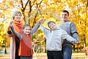 Happy family walks in autumn city park. Children and parents posing, smiling, playing and having fun. Bright yellow trees.