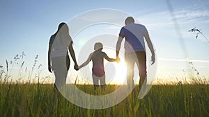 Happy family walks in the park in the sun at sunset. Mom, dad and kid happy walk at sunset in the park. Joint family