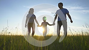 Happy family walks in the park in the sun at sunset. Mom, dad and kid happy walk at sunset in the park. Joint family