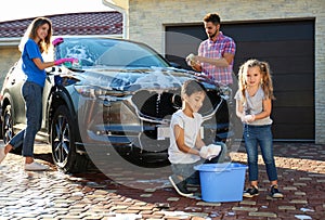 Happy family washing car at backyard