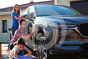 Happy family washing car at backyard