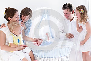 Happy family watching new baby in a white crib