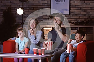 Happy family watching TV on sofa in evening