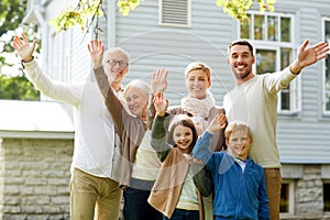 Happy family waving hands in front of house