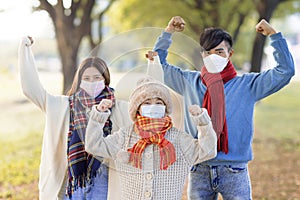 Happy family wearing medical mask and walking in the fall park