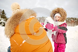 Happy family in winter clothes playing with snow