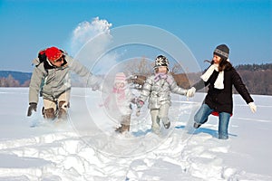 Happy family in winter, having fun with snow outdoors