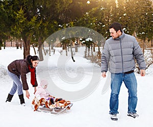 Happy family in winter park. Baby on the sled In the snow