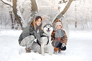 Happy family in the winter park plays about Huskies.