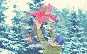 Happy family on winter walk. Dad throws up baby girl