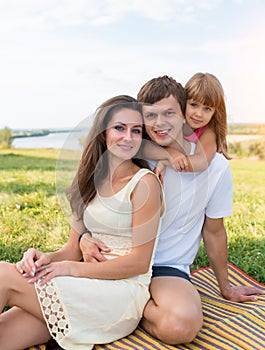 Happy family, woman mom with man dad, girl daughter 5-6 years old, fun joyful outdoor picnic, parenting, emotions of