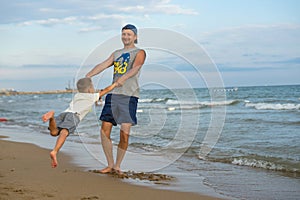 Happy family. Young beautiful father and his smiling son baby boy having fun on the beach of the sea, ocean. Positive human emotio