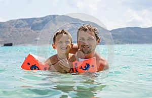 Happy family. Young beautiful father and his smiling son baby boy having fun on the beach of the sea, ocean. Positive human emotio