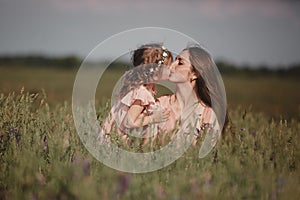Happy family: a young beautiful pregnant woman with her little cute daughter walking in the wheat field on a sunny