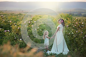 Happy family: a young beautiful pregnant woman with her little cute daughter walking in the wheat orange field on a