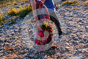 Happy family: young beautiful pregnant woman, a man walking along the sea stones on Sunnset summer day photo