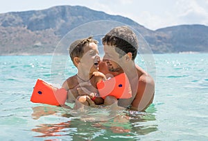 Happy family. Young father and his beautiful smiling son baby boy having fun on the beach of the sea, ocean. Positive human