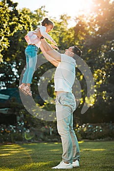 Happy family. Young mixed race father playing with his little daughter lifting her up while they laugh and smile in the