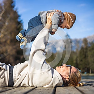 Happy family. Young mother playing with her baby boy infant oudoors on sunny autumn day. Portrait of mom and little son