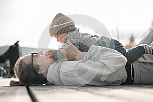 Happy family. Young mother playing with her baby boy infant oudoors on sunny autumn day. Portrait of mom and little son