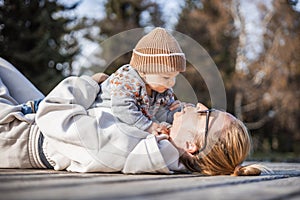 Happy family. Young mother playing with her baby boy infant oudoors on sunny autumn day. Portrait of mom and little son