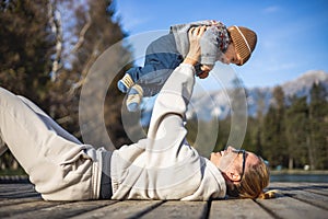 Happy family. Young mother playing with her baby boy infant oudoors on sunny autumn day. Portrait of mom and little son