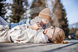 Happy family. Young mother playing with her baby boy infant oudoors on sunny autumn day. Portrait of mom and little son