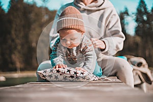 Happy family. Young mother playing with her baby boy infant oudoors on sunny autumn day. Portrait of mom and little son