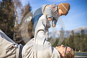 Happy family. Young mother playing with her baby boy infant oudoors on sunny autumn day. Portrait of mom and little son