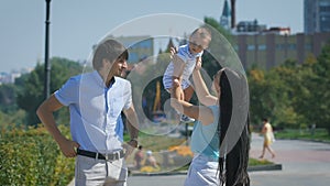 Happy family. Young mother throws up baby in the sky, on sunny day.