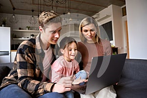 Happy family young parents and child daughter using laptop computer at home.