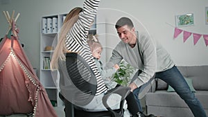 happy family, young parents woman and man with joyful daughter have fun together, man rolls his wife and daughter on