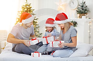 Happy familymother father and child on Christmas morning in bed