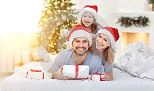 Happy familymother father and child on Christmas morning in bed