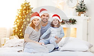 Happy familymother father and child on Christmas morning in bed