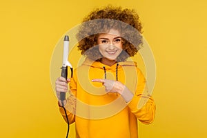 Happy fancy hipster woman with perfect afro hairdo showing iron curler, professional curling tong