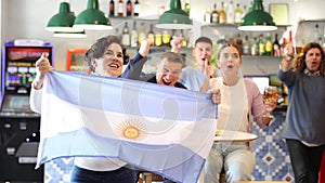 Happy fans celebrating the victory of Argentinean team in the bar