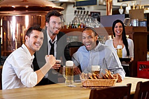 Happy fans watching TV in pub cheering