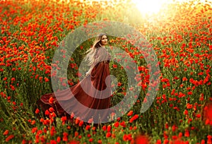 Happy fantasy woman queen in red silk dress, walking in poppy field, summer green grass, nature flowers. Girl goddess