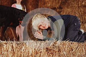 Happy farm kids playing on hay stack with pet rottweiler dog